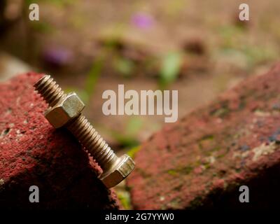 Nut bolt hardware presented on brick surface for industrial background. Stock Photo