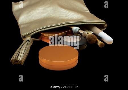 Cosmetic bag with beauty accessories and makeup products isolated on black Stock Photo