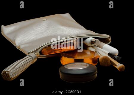 Cosmetic bag with beauty accessories and makeup products isolated on black Stock Photo