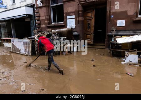 Bad Neuenahr, Germany. 16th July, 2021. A woman pushes mud through the street. Massive rainfall has caused flooding in Bad Neuenahr in Rhineland-Palatinate as well as in the entire district of Ahrweiler. Credit: Philipp von Ditfurth/dpa/Alamy Live News Stock Photo