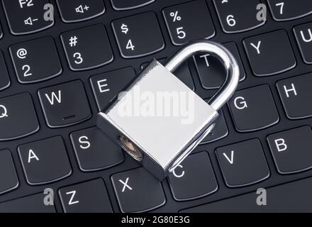Computer security concept. Silver padlock on black laptop keyboard Stock Photo