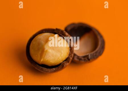 split macadamia nut close-up on an orange background. Stock Photo