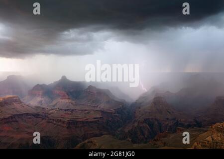 Lightning strikes the walls of the canyon as rain from a monsoon storm drifts across Grand Canyon National Park, Arizona Stock Photo