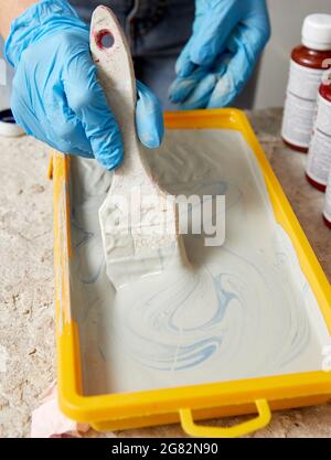 Cropped view of hand wearing gloves using paint brush and paint Stock Photo