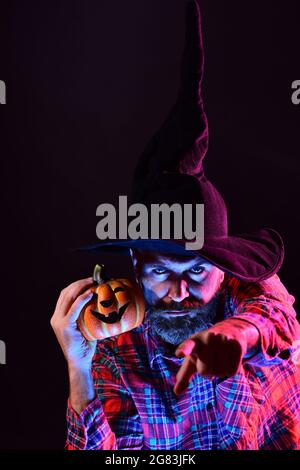 Background decorated for Halloween. Witch hat. Man on the Horror background. Halloween Witch with a carved Pumpkin and magic lights in a dark forest Stock Photo