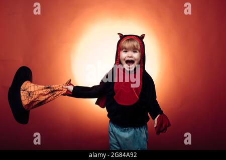 Halloween Witch with a carved Pumpkin and magic lights in a dark forest. Children play with pumpkins and treat. Halloween dresses and witch costumes Stock Photo