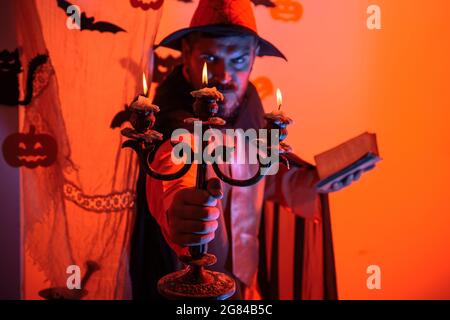 Man on the Horror background. Halloween Witch with a carved Pumpkin and magic lights in a dark forest. Halloween party for happy family. Witch hat Stock Photo