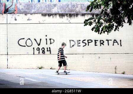 Teenage boy skateboarding in front of Covid-19 graffiti, Barcelona, Spain. Stock Photo