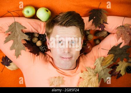 Happy young man are preparing for autumn sunny day. Fashion man. Surprise read head man playing with leaves and looking at camera. Stock Photo