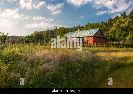 Beautiful, old, polish village with traditional agricultural buildings situated in the middle of the forest in the morning light. Krasnobród, Roztocze Stock Photo