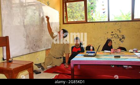 teacher with disabilities (without legs), eagerly teaches his students at a school Stock Photo