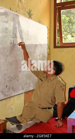 teacher with disabilities (without legs), eagerly teaches his students at a school Stock Photo