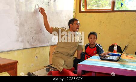 teacher with disabilities (without legs), eagerly teaches his students at a school Stock Photo