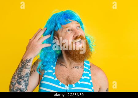 Happy man with life buoy, swimsuit and blue wig acts like a happy woman Stock Photo