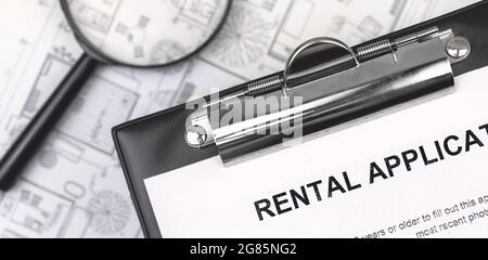 Rental agreement form close-up. Contract on clipboard close-up. Background with magnifying glass. Banner Stock Photo