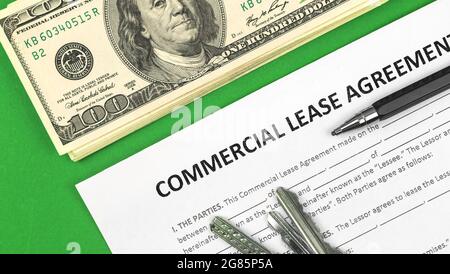 Commercial lease form close-up. Dollars, pen and house keys on green office table. Top view Stock Photo