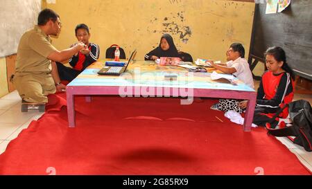 teacher with disabilities (without legs), eagerly teaches his students at a school Stock Photo