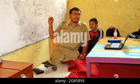 teacher with disabilities (without legs), eagerly teaches his students at a school Stock Photo