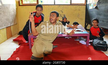 teacher with disabilities (without legs), eagerly teaches his students at a school Stock Photo