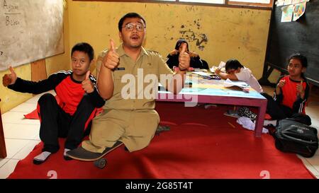 teacher with disabilities (without legs), eagerly teaches his students at a school Stock Photo