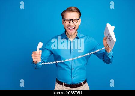 Photo of young man angry mad crazy scream boss fail trouble hold phone isolated over blue color background Stock Photo