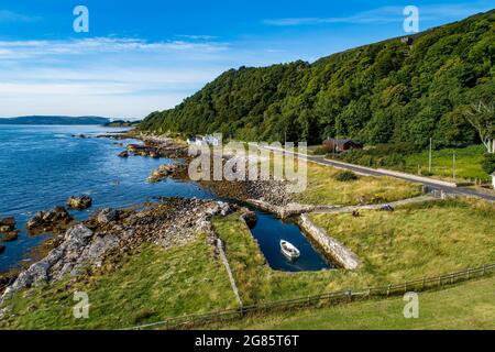 Northern Ireland, UK. Atlantic coast at Garron Point. Causeway Costal Route. One of the most scenic coastal roads in Europe. Small marina with a boat. Stock Photo