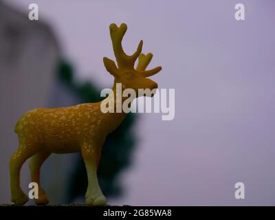 Deer animal toy presented at natural green leaves with sky backdrop, kids playing object natural image. Stock Photo