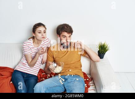 young couple sitting next to popcorn watching tv rest Stock Photo