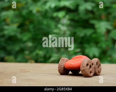 hand made clay art car presented on stone surface at natural green blur leaves park background. Stock Photo