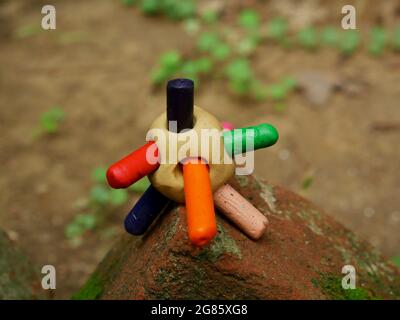 Multiple color pen inserted into clay soil presented on brick at blur soil field. Stock Photo