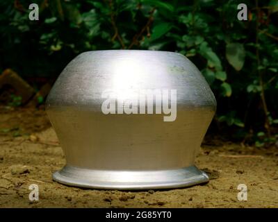 Single silver metal food cooking bowl kept on soil land, kitchen cutlery product image. Stock Photo
