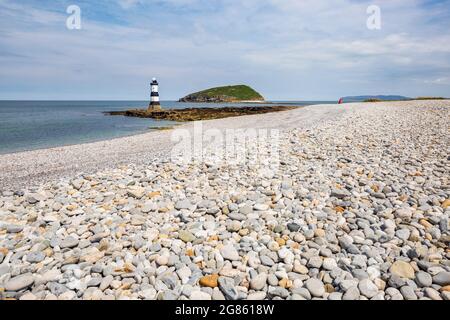 The pebble beach at Penmon Point with the lighthouse and Puffin Island in the background, Anglesey, North Wales Stock Photo