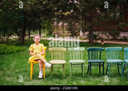 lifestyle portrait of a girl in dresses sitting on chairs in an open-air cinema in the backyard, family vacation on weekends on summer evenings Stock Photo