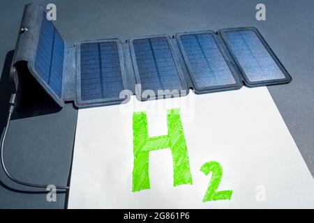 Green hydrogen concept. Solar panel connected to H2 text, symbolizing the generation of hydrogen from solar energy without fossil fuels. Stock Photo