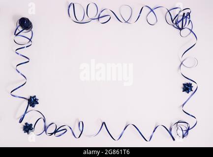 Frame from blue ribbon with gift bows on a white background with copy space. Stock Photo