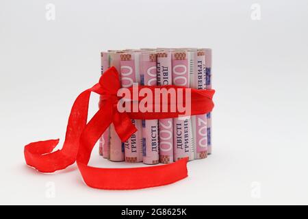 200 gryvnias in a roll with a red gift ribbon. On a white background. Stock Photo