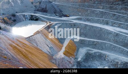 Aerial view on gravel quarry with terraces, pool of water and stone crusher machine