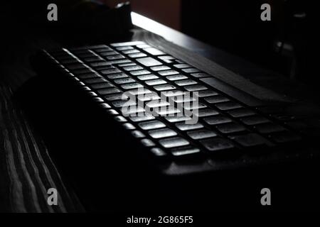 Computer wireless keyboard with control, function and navigation alphanumeric keys and numeric keypad on wooden table background on the office in moon Stock Photo
