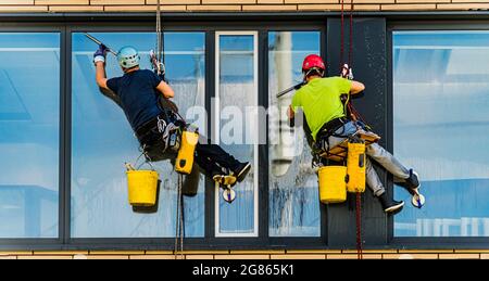 Two men cleaning windows on an office building Stock Photo