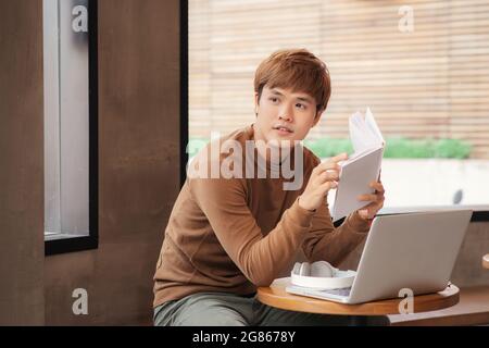 young serious asian man studying or working in coffee house Stock Photo