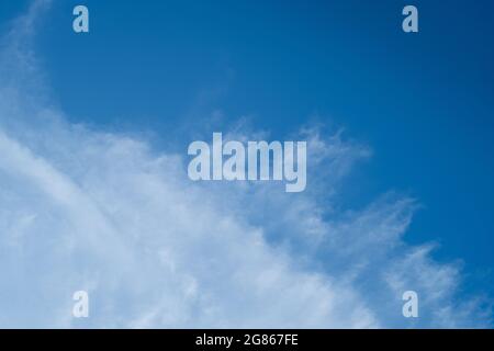 Whispy white clouds and blue sky diving frame diagonally with negative space for copy Stock Photo