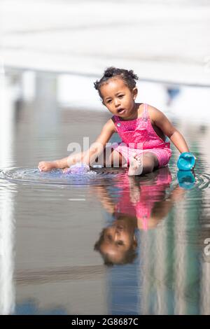 Birmingham, UK. 17th July, 2021. Two year old Grace has a splashing time in the fountains in Birmingham's Centenary Square. Peter Lopeman/Alamy Live News Stock Photo