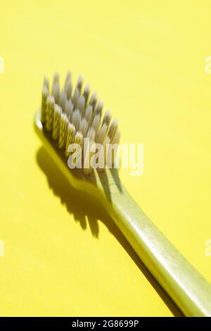 Green plastic toothbrush on sunny yellow table. Stock Photo