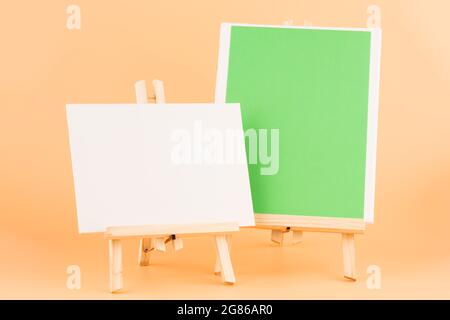 Two wooden easels with blank canvases on yellow background. Stock Photo