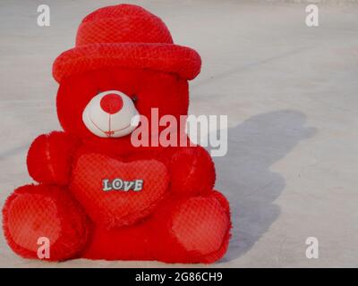 Teddy bear Animal red color soft toy standing with shadow reflection on cemented surface, kids playing object image Stock Photo