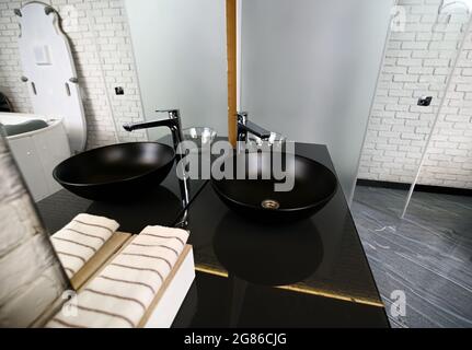 Luxurious washbasin on a black marble countertop in a wellness spa clinic with modern equipment. Stock Photo