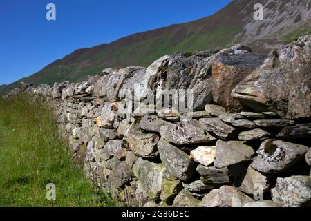 Traditional sry stone wall on farmland in the Welsh mountains. On a summers day with blue sky Stock Photo
