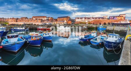 A lovely still morning with the colourful boats reflected in the harbour at Seahouses on the Northumberland coast in England, Uk Stock Photo