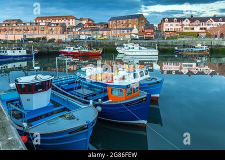 A lovely still morning with the colourful boats reflected in the harbour at Seahouses on the Northumberland coast in England, Uk Stock Photo