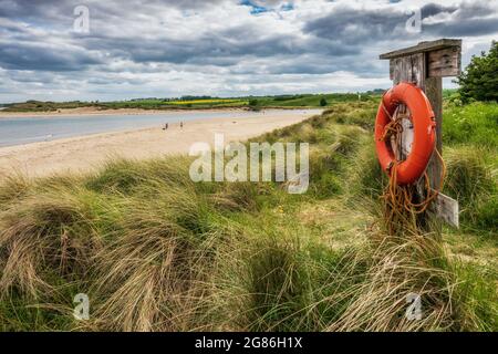 A lifebuoy at Alnmouth beach in Northumberland, standing guard on the dunes, looking out to sea. Stock Photo